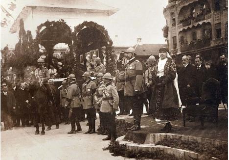 ORAȘ ÎN SĂRBĂTOARE. 23 mai 1919 a găsit Oradea împodobită mai frumos ca oricând, totul fiind minuțios pregătit pentru prima vizită oficială a Regelui Ferdinand I și a Reginei Maria. Întreg centrul, de la gară până în piața centrală, a fost decorat cu drapele și flori, în fața Palatului Vulturul Negru fiind amenajat un podium pentru primirea Suveranilor. Aceștia au asistat la o defilare spectaculoasă, au luat pulsul orașului și au ascultat doleanțele locuitorilor (foto: Aurel Chiriac (editor), Primăvara întregirii, 2019)