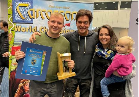 ÎMPREUNĂ. La Essen, Gere Árpád (stânga) a fost susținut de soția Leona, și fetița Kincső (dreapta), iar în final a fost felicitat chiar de creatorul jocului Carcassonne, germanul Klaus-Jürgen Wrede (în mijloc), care i-a înmânat trofeul și diploma de campion mondial