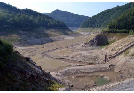 VEDERE RARĂ. Turiştii care urcă la barajul Leşu au parte de un peisaj nemaivăzut din 1993: lacul a fost golit cu totul. Pe cele peste 100 de hectare ale acumulării mai curge doar Valea Iadului, şerpuind printre zidul barajului şi stâncile muntelui