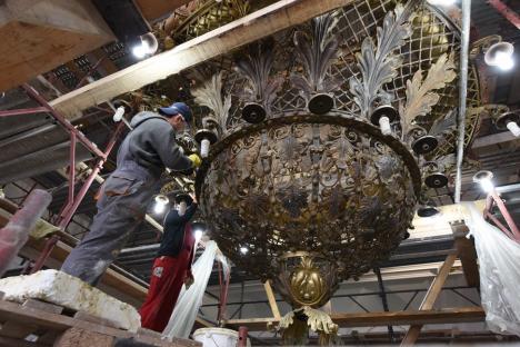 IMAGINI RARE: Uriașul candelabru din sala mare a Primăriei Oradea a fost coborât pentru a fi îmbrăcat în aur